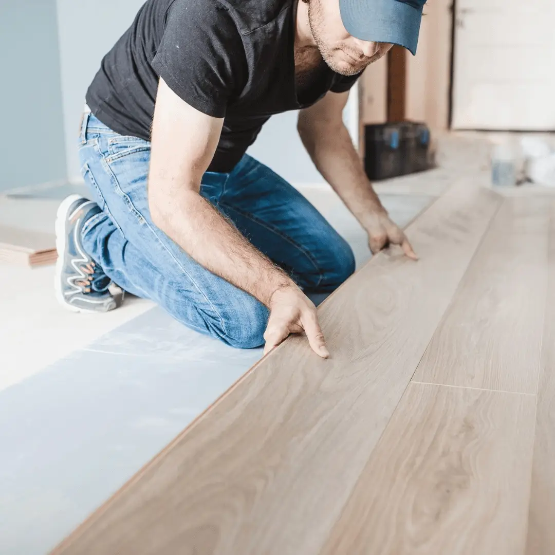 Installer positioning a new wide-plank engineered hardwood board during installation