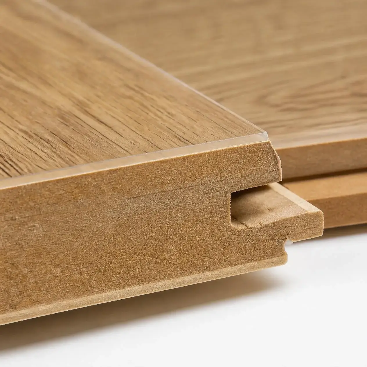 Close-up of a laminate plank edge showing the wear layer, printed oak decor layer, HDF core and click-lock profile