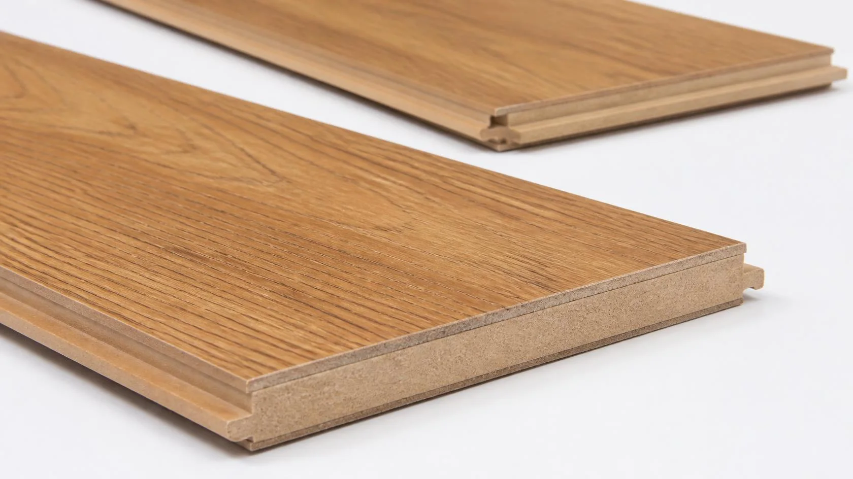 Close-up of a laminate plank edge showing the wear layer, printed oak decor layer, HDF core and click-lock profile