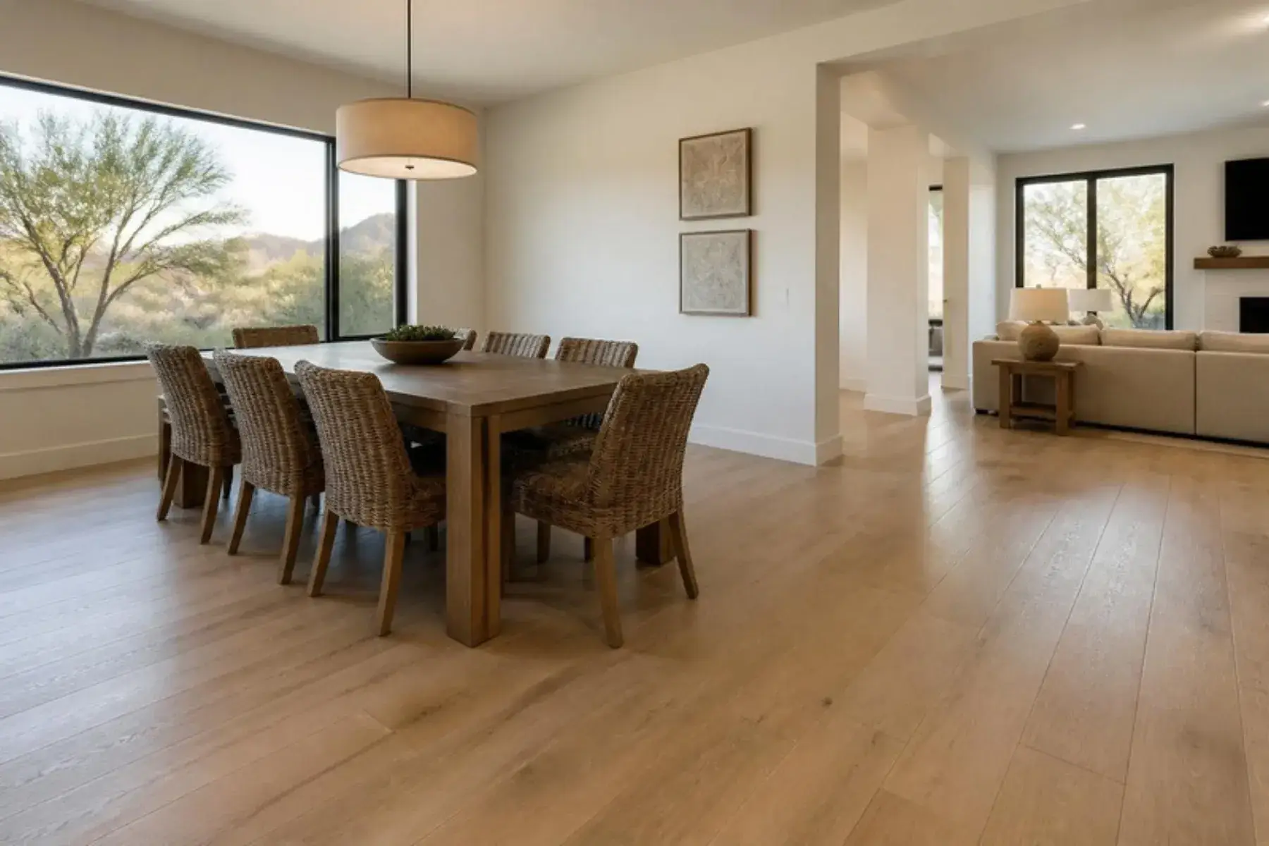 Dining area and family room with continuous pale oak-look laminate plank flooring and desert hills outside