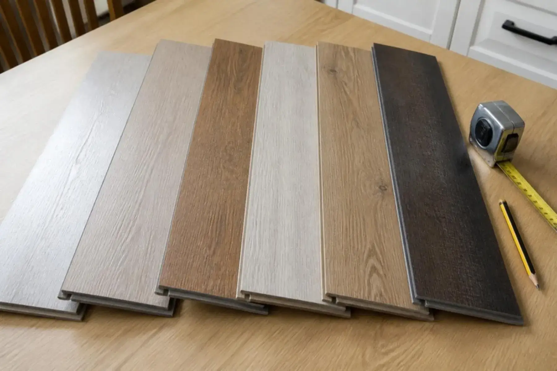 Six laminate flooring samples from whitewashed oak to dark walnut laid side by side for comparison